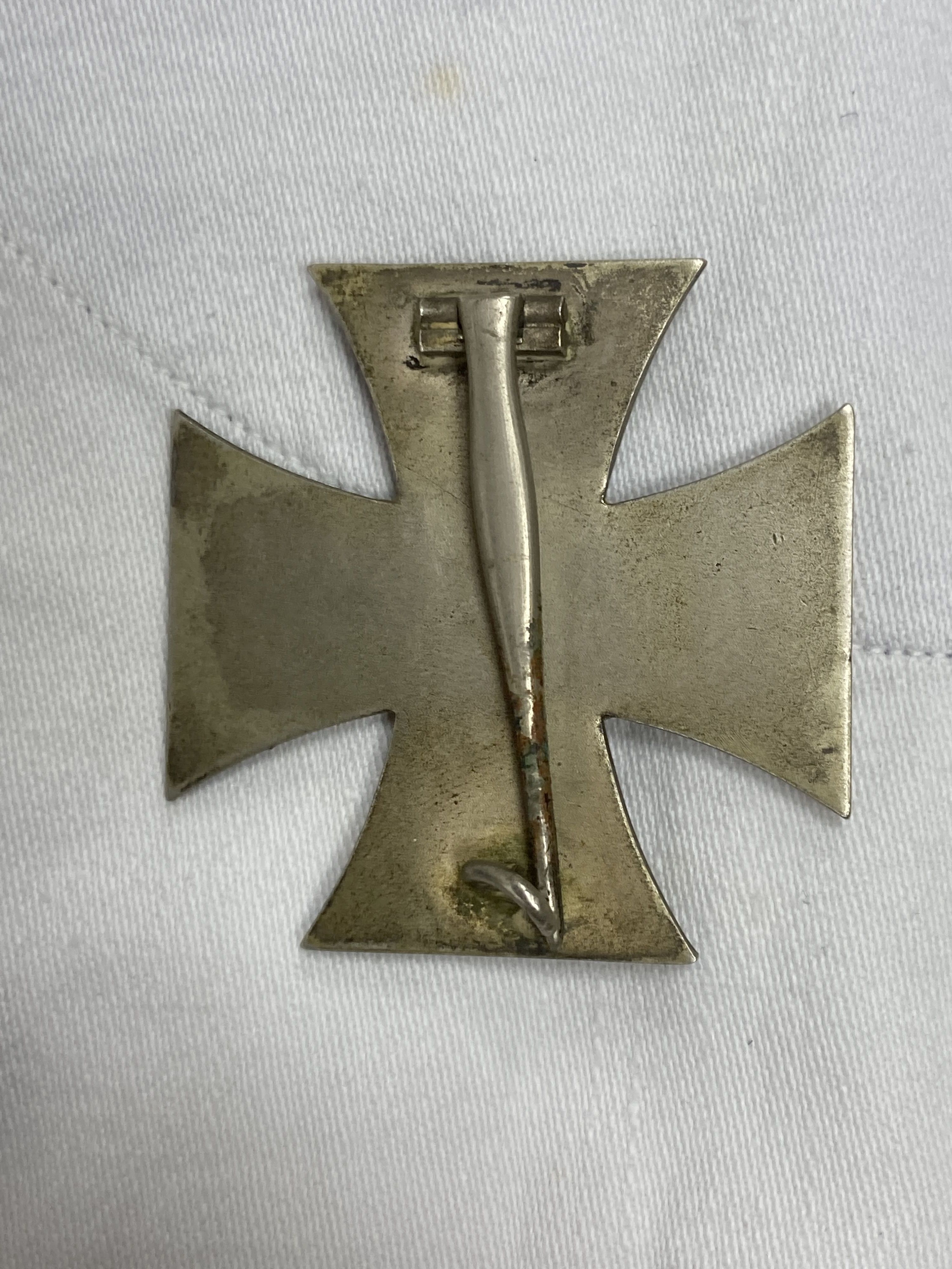 Two German  period white naval tunics, one named 'Schmidt. R, X176 T', together with an associated 1939 iron cross (3)